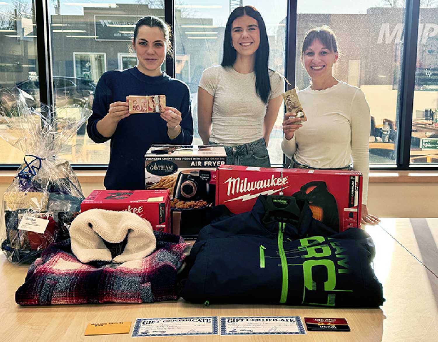 The World-Spectators Nicole Taylor, Joey Light, and Kara Kinna with some of the prizes that will be given away in the World-Spectator Christmas Giveaway.